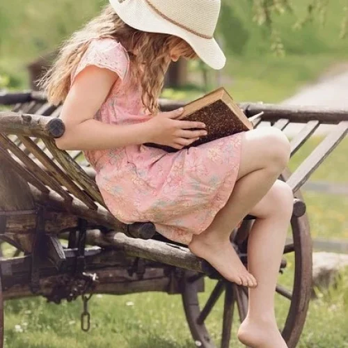 petite fille en train de lire assise sur une charrette